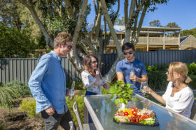 Image of 4 people having a casual drink in a backyard with grey Colorbond fencing in the background